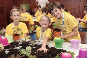 Drei Buben bepflanzen bei der 3. Kinder Business Week bunte Töpfe