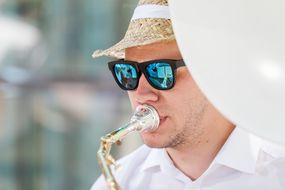 Musiker spielt mit Sonnenbrille und Sonnenhut am Straßenfest zum Weltspieltag ein Instrument