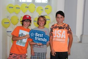 Drei Buben halten bei den NÖ KinderSommerSpielen 2016 ein Kind mit "Best Friends" in die Kamera.