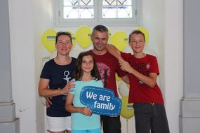 Eine Familie hält bei den NÖ KinderSommerSpielen 2016 ein Schild mit "We are familiy" in die Kamera.