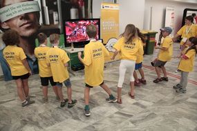 Kinder in gelben T-Shirts tanzen.