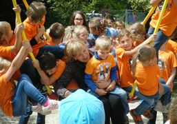 Landesrätin Schwarz schaukelt zusammen mit Kindern in orangen T-Shirts.