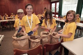 Vier Kinder entnehmen aus Säcken getrocknete Teeblätter bei der 3. Kinder Business Week