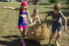 Drei Kinder schleppen beim Eltern-Kind Bau- & Spieletag in Kilb einen Strohballen ins Tipi.