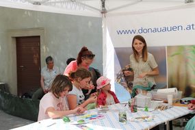 Kinder bemalen beim Familienfest Donau-Auen Steine mit bunten Farben