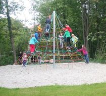 Kinder klettern auf einer Pyramide aus bunten Stricken