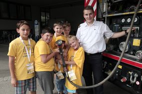 Kinder halten den Wasserschlauch eines Feuerwehrautos bei der 3. Kinder Business Week