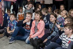 Kinder sitzen bei gemeinsamer Auftaktveranstaltung mit 30 Gemeinden am Boden und hören gespannt zu