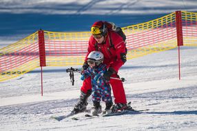 Ein Erwachsener und ein Kind üben das Skifahren
