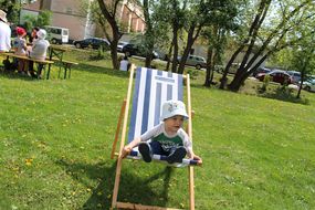 Bub genießt das schöne Wetter beim Familienfest Donau-Auen in einem blau-weiß gestreiften Liegestuhl