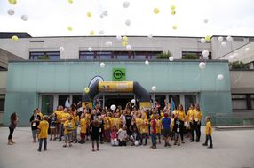 Die Teilnehmerinnen und Teilnehmer lassen gelbe und weiße Luftballons aufsteigen.