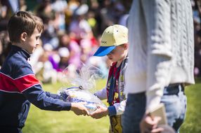 Bub übergibt einem anderen Bub in durchsichtigem Geschenkpapier eingepackte Spiele beim NÖ Familienfest auf der Schallaburg 2018