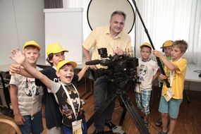 6 Kinder und ein Kameramann stehen neben dem Kamera-Equipment.