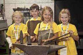 Vier Kinder in gelben T-Shirts lächeln bei der 3. Kinder Business Week in NÖ in die Kamera