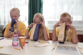 Kinder riechen an einem Säckchen voll getrocknetem Tee bei der 3. Kinder Business Week