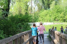 Zwei Frauen und ein Kind überqueren eine Holzbrücke beim Familienfest Donau-Auen
