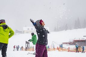 Eine Frau wirft Schnee in die Luft und streckt sich beim Familienskitag am 21. Jänner 2018
